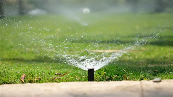 active lawn sprinkler watering grass with a fine mist in a sunny residential yard