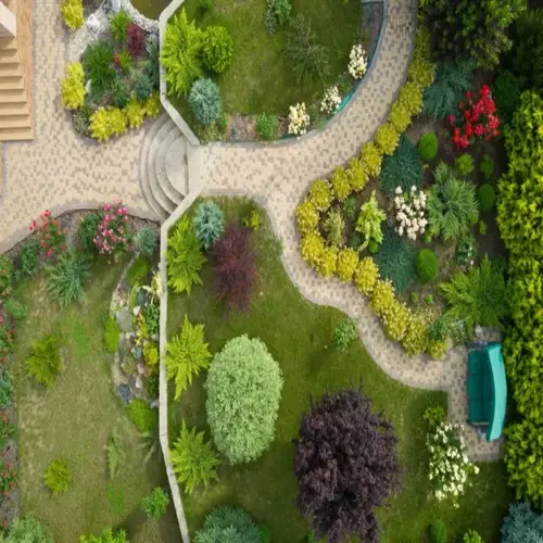 aerial view of a drought resistant perennial garden with winding pathways, lush greenery, and a green bench