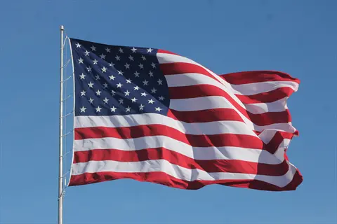 american flag with stars and stripes waving in the wind against a blue sky, no leeks shown
