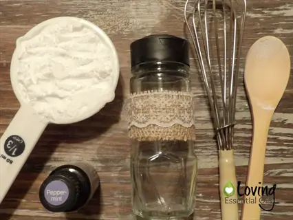baking soda box garden setup with measuring cup of baking soda, peppermint essential oil, glass jar with lace, whisk, and wooden spoon on a wooden surface