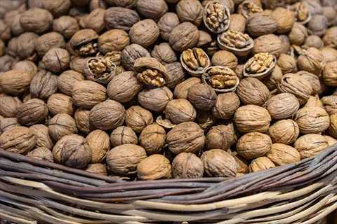 basket filled with whole and halved walnuts, showcasing a harvested walnut collection