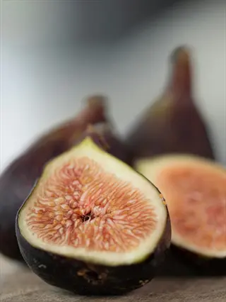 black mission fig dark fruits: whole and sliced figs revealing pink flesh with tiny seeds, soft focus background