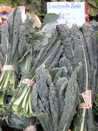 bunches of lacinato kale leaves with price sign at a market