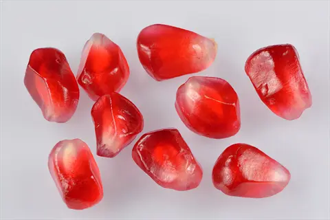 close-up of juicy red eversweet pomegranate arils on a white background