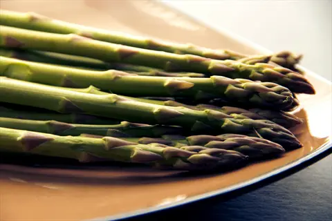 fresh purple asparagus spears (purple passion variety) with green stems and purple-tinged tips arranged on a plate