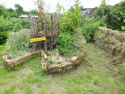 keyhole garden raised bed with text sign and brick border