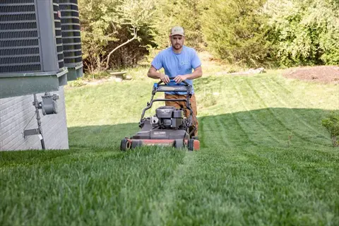 man mowing residential lawn at optimal height to maintain healthy grass