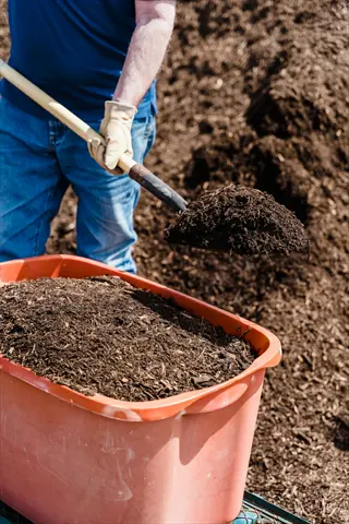 mixing soil bucket garden with shovel and person in gloves
